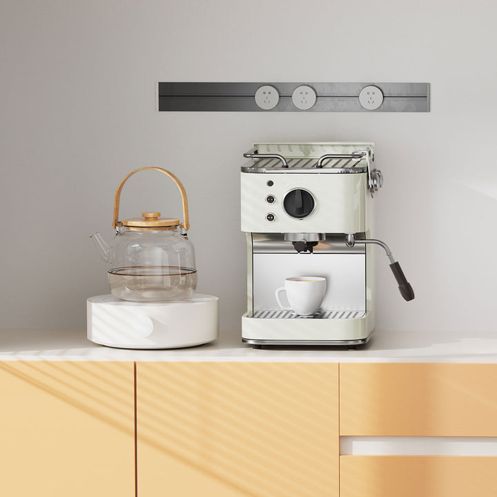 White espresso machine on a kitchen counter with a glass teapot and cup.