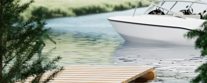 White boat on a dock by a body of water with greenery